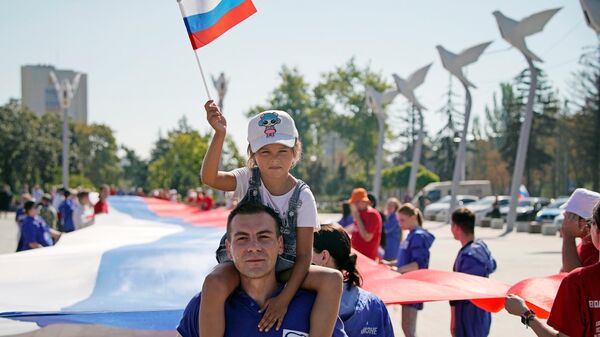Участники праздничных мероприятий, приуроченных ко Дню российского флага, на площади Ленина в Мариуполе