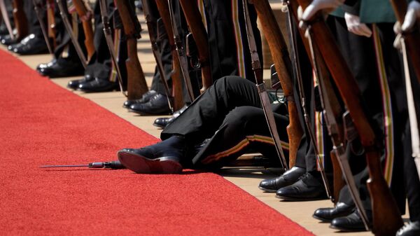Член президентского почетного караула сидит на полу из-за недомогания в преддверии церемонии приветствия государственного визита председателя КНР Си Цзиньпина в Юнион Билдинг в Претории, ЮАР