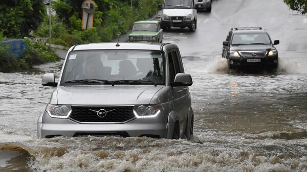 Автомобили едут по одной из улиц Владивостока, затопленной в результате сильного ливня