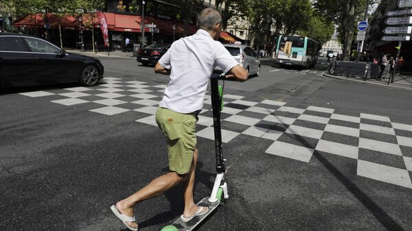 Мужчина едет на электросамокате в Париже
