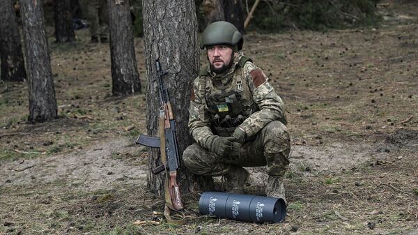 Украинский военнослужащий перед снарядом от 155-миллиметровой гаубицы ТРФ-1