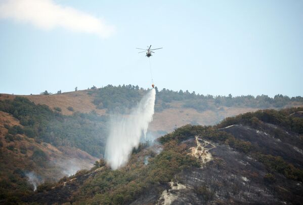 Вертолет сбрасывает воду на месте тушения лесного пожара в Геленджике