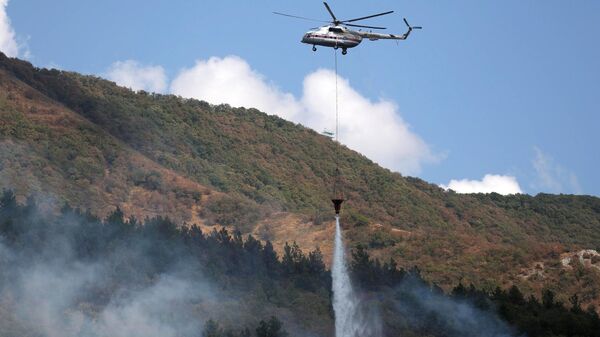 Вертолет сбрасывает воду на месте тушения лесного пожара в Геленджике
