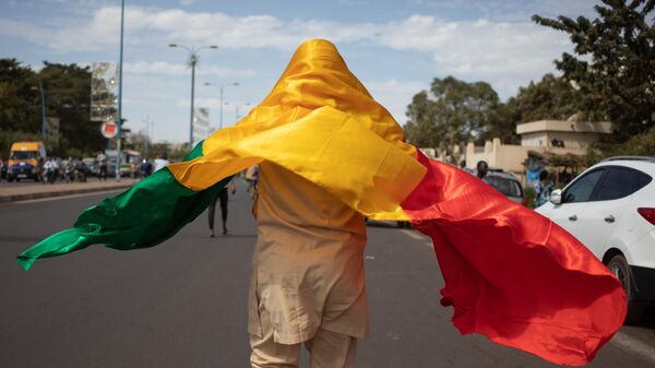 Мужчина с флагом Мали на улице Бамако