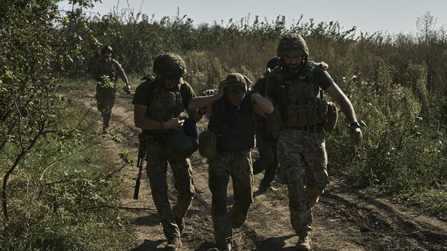 Украинские военнослужащие эвакуируют раненого солдата