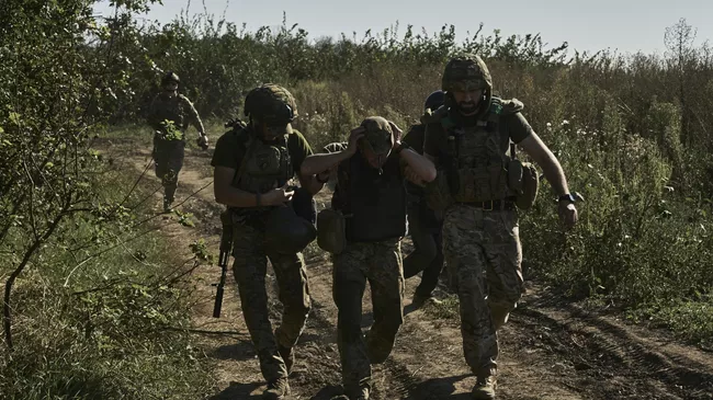 Украинские военнослужащие эвакуируют раненого солдата