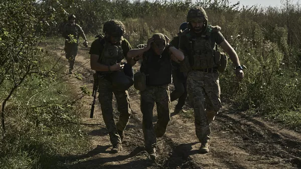 Украинские военнослужащие эвакуируют раненого солдата