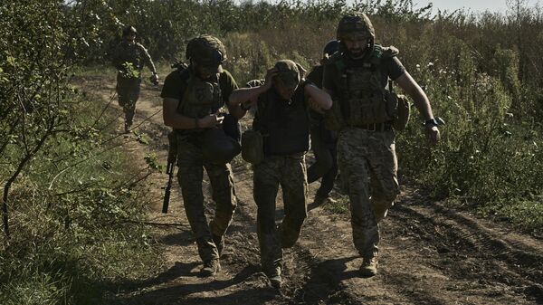 Украинские военнослужащие эвакуируют раненого солдата на передовой в Донецкой области