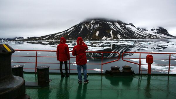 Участники детского тематического рейса на Северный полюс фотографируют один из островов в составе архипелага Земля Франца-Иосифа