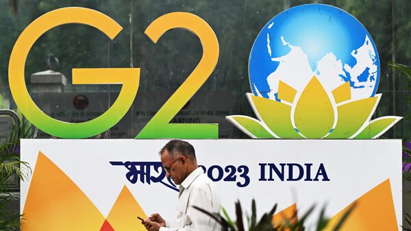 Мужчина проходит мимо баннера установленного к саммиту G20 на улице в Нью-Дели