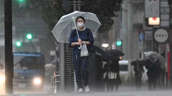 Девушка под проливным дождем, вызванным приближающимся тайфуном в Токио