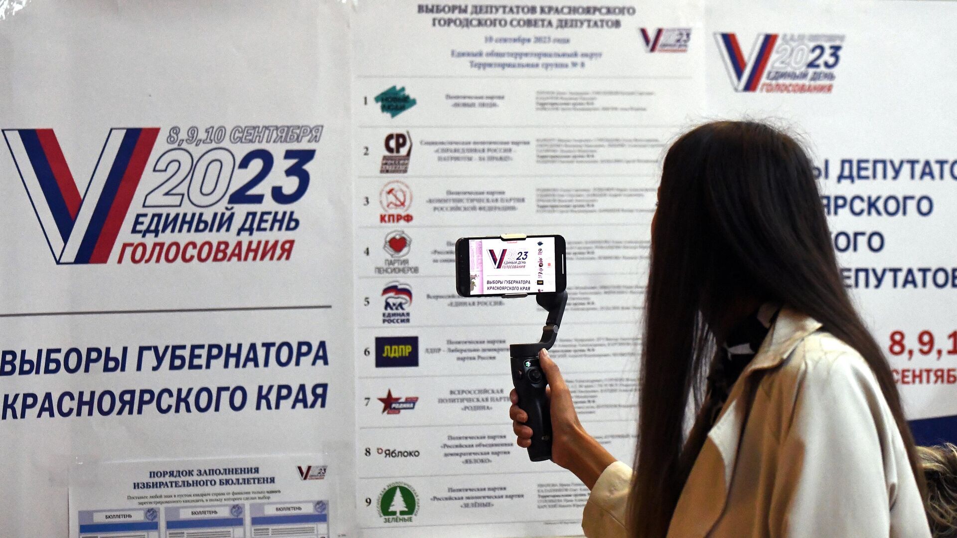 Девушка фотографирует информационный стенд на выборах - РИА Новости, 1920, 08.09.2023