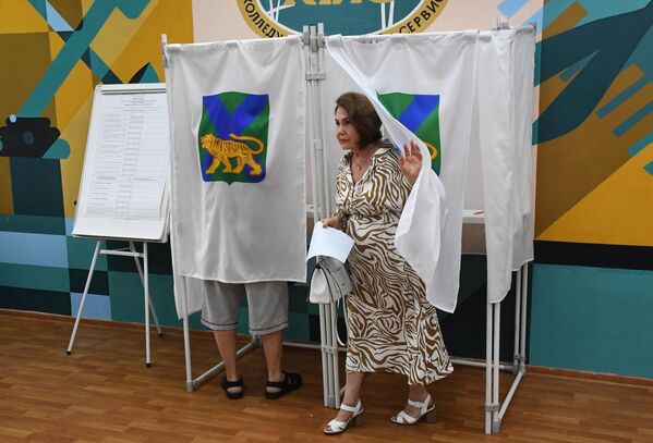Женщина голосует на выборах главы Приморского края на избирательном участке во Владивостоке