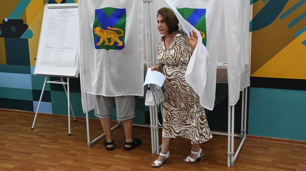 Женщина голосует на выборах главы Приморского края на избирательном участке во Владивостоке