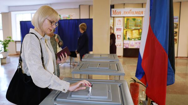 Женщина голосует на выборах в парламент и органы самоуправления в Единый день голосования на одном из избирательных участков в Донецке