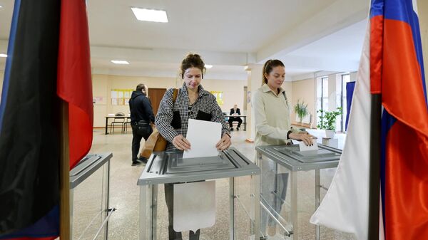 Девушки голосуют на выборах в парламент и органы самоуправления в единый день голосования на одном из избирательных участков в Донецке