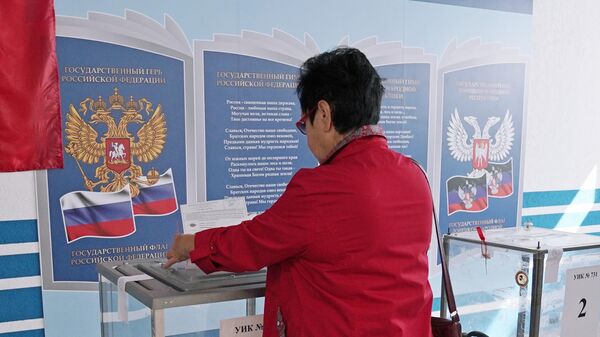 Женщина голосует на выборах в парламент и органы самоуправления в Единый день голосования на избирательном участке в Мариуполе