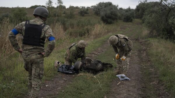 Украинские военнослужащие осматривают тело солдата в Харьковской области, 17 сентября 2022 года
