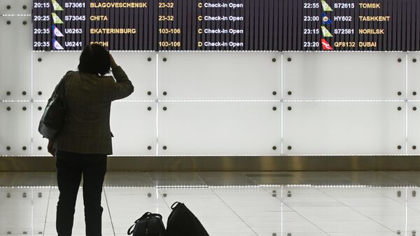 Женщина возле электронного табло вылетов в аэропорту Домодедово в Москве