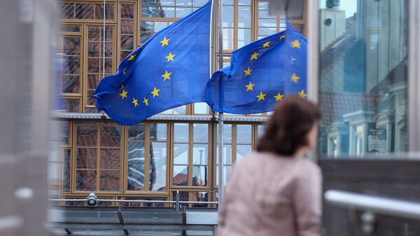 Женщина проходит мимо флагов ЕС в Брюсселе