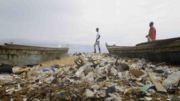 Люди гуляют по замусоренному пляжу в Кот-д’Ивуаре