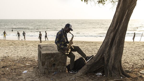 Мужчина играет на саксофоне на пляже Ламли в Сьера-Леоне