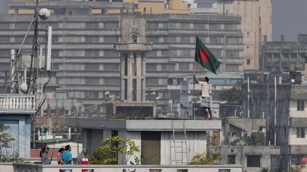 Мужчина поднимает национальный флаг Бангладеш