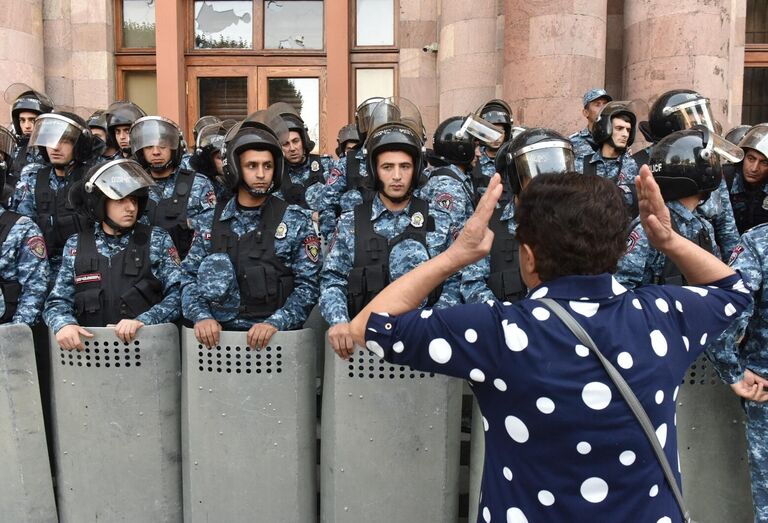 Участница протеста на фоне эскалации в Нагорном Карабахе и сотрудники полиции на площади Республики в Ереване