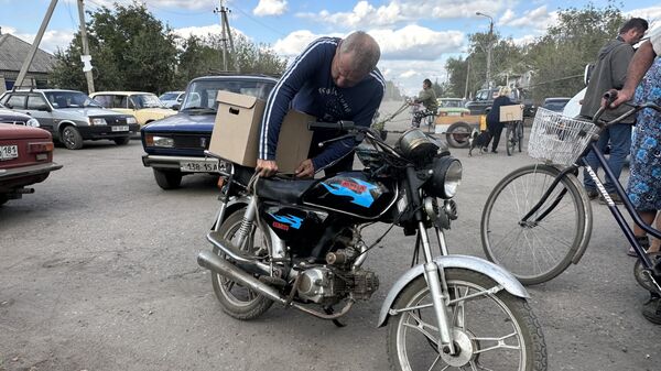Житель села Нижнее крепит продуктовый набор на мотоцикл