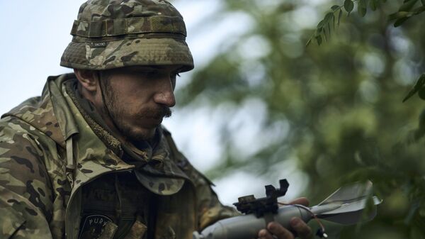 Солдат армии Украины загружает бомбу на беспилотник