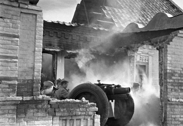 Южный фронт (с 20 октября 1943 — 4-й Украинский фронт). Советские артиллеристы бьют прямой наводкой по засевшим в соседних зданиях немцам,  уличные бой в Мелитополе. Октябрь, 1943 года
