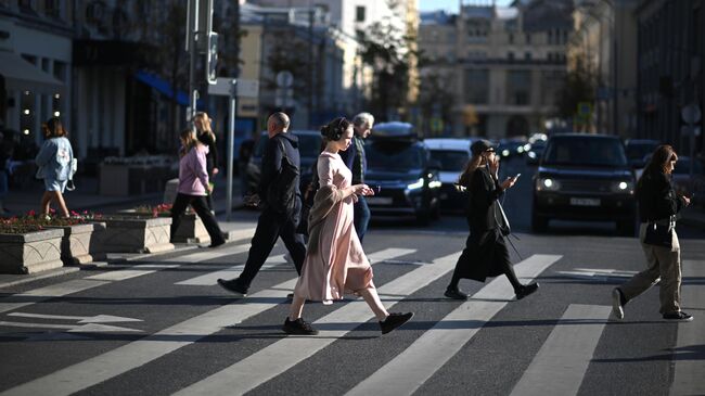 Люди переходят дорогу на Неглинной улице в Москве