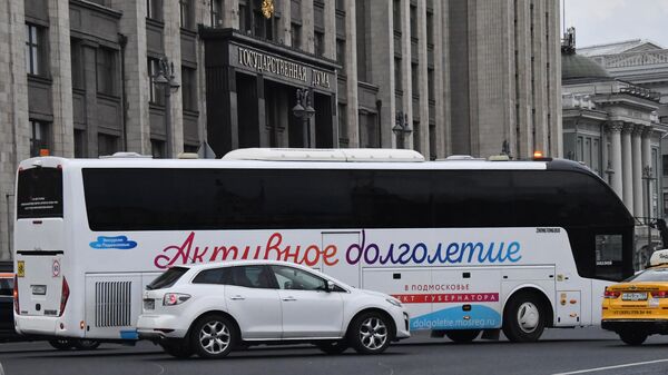 Экскурсионный автобус с символикой проекта губернатора Московской области Активное долголетие у здания Государственной Думы РФ в Москве