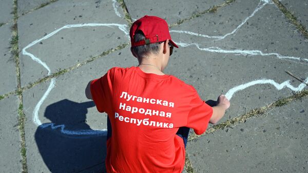 Мальчик рисует на асфальте во время праздничных мероприятий, посвященных Дню воссоединения новых регионов с Россией, в Луганске