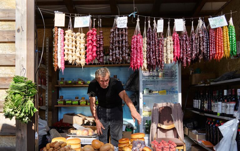 Продавец чурчхелы за прилавком на рынке в городе Новый Афон в Абхазии