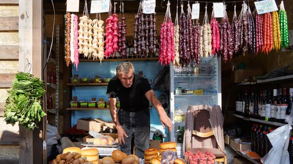 Продавец чурчхелы за прилавком на рынке в городе Новый Афон в Абхазии