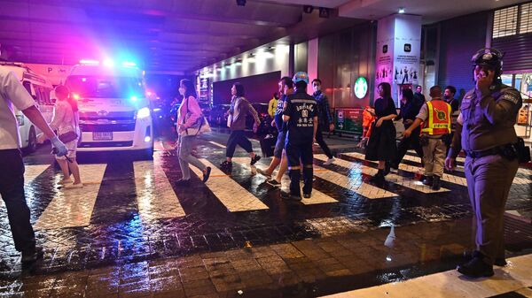 Сотрудники экстренных служб и посетители у входа в торговый центр Siam Paragon в Бангкоке после стрельбы
