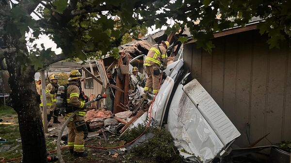 Пожарные на месте происшествия, где самолет врезался в крышу дома, в Ньюберге, США