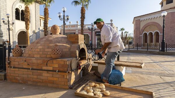 Пекарь готовит египетские лепешки эйш балади в кирпичной печи в Шарм-эш-Шейхе