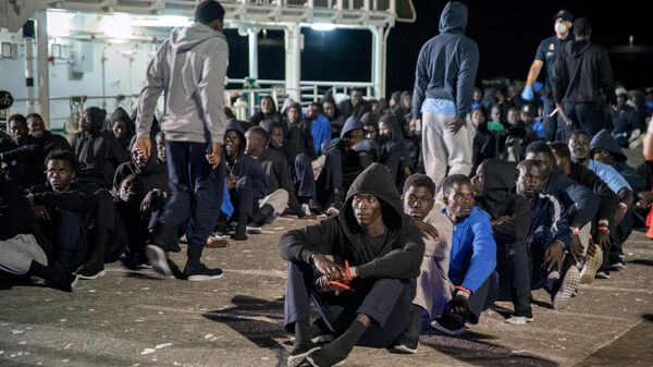 Мигранты сидят на причале после прибытия судна на острове Канарского архипелага Иерро