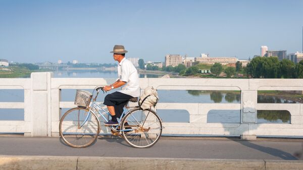 Мужчина едет на велосипеде по улице Пхеньяна
