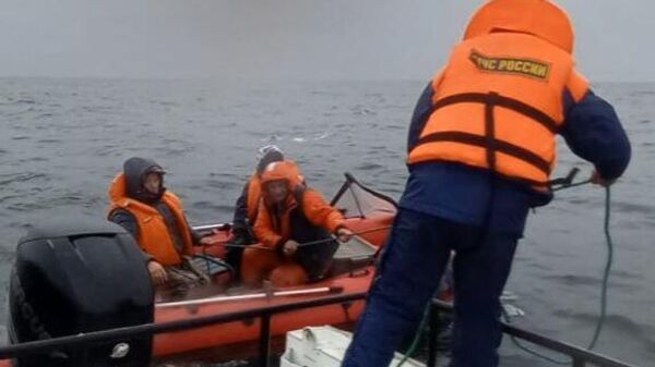 Сотрудники МЧС оказывают помощь рыбакам, лодку которых стало уносить в открытое море 