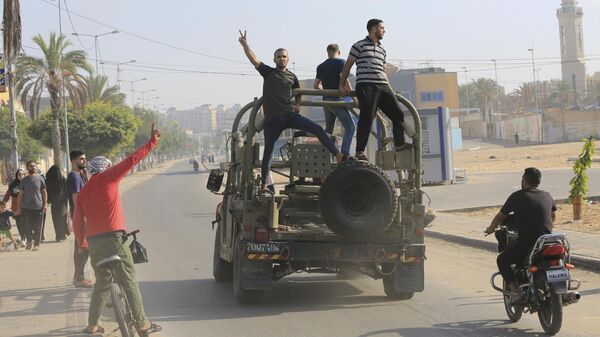 Палестинские бойцы едут на захваченной израильской военной машине в секторе Газа
