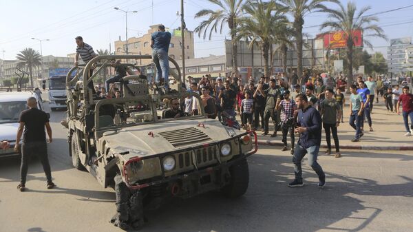 Палестинские бойцы едут на захваченной израильской военной машине в секторе Газа
