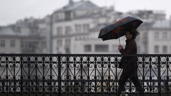 Мужчина под зонтом на одной из улиц в центре Москвы