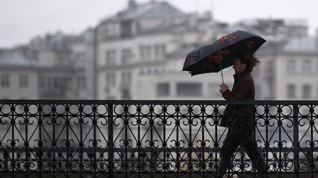 Мужчина под зонтом на одной из улиц в центре Москвы. Архивное фото