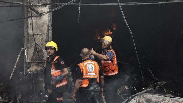 Палестинские пожарные на месте пожара, начавшегося после авиаудара Израиля по лагерю беженцев Джабалия в секторе Газа