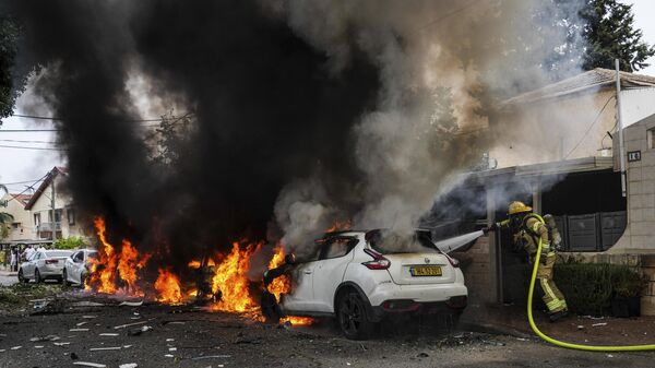 Израильские пожарные ликвидируют пожар на месте попадания ракеты, выпущенной из сектора Газа