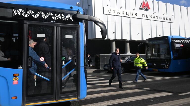 Люди в бесплатном автобусе КМ у вестибюля станции метро Печатники в Москве