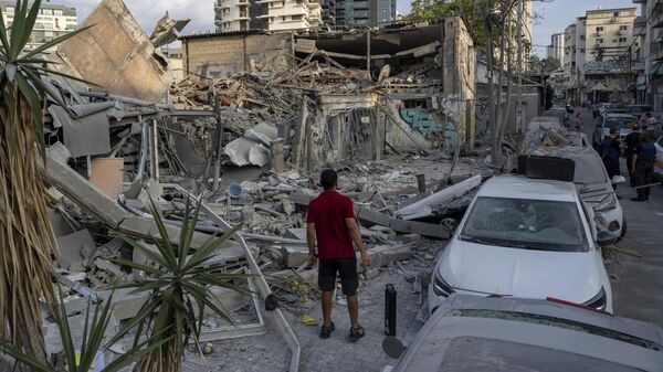Израильтяне среди развалин здания после попадания в него ракеты, выпущенной из сектора Газа